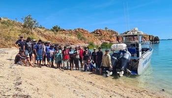 Group of people standing next to boat on shoreline