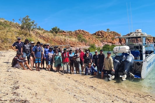 Group of people standing next to boat on shoreline