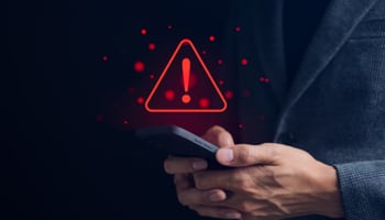 Person holding smartphone with red alert icon over image