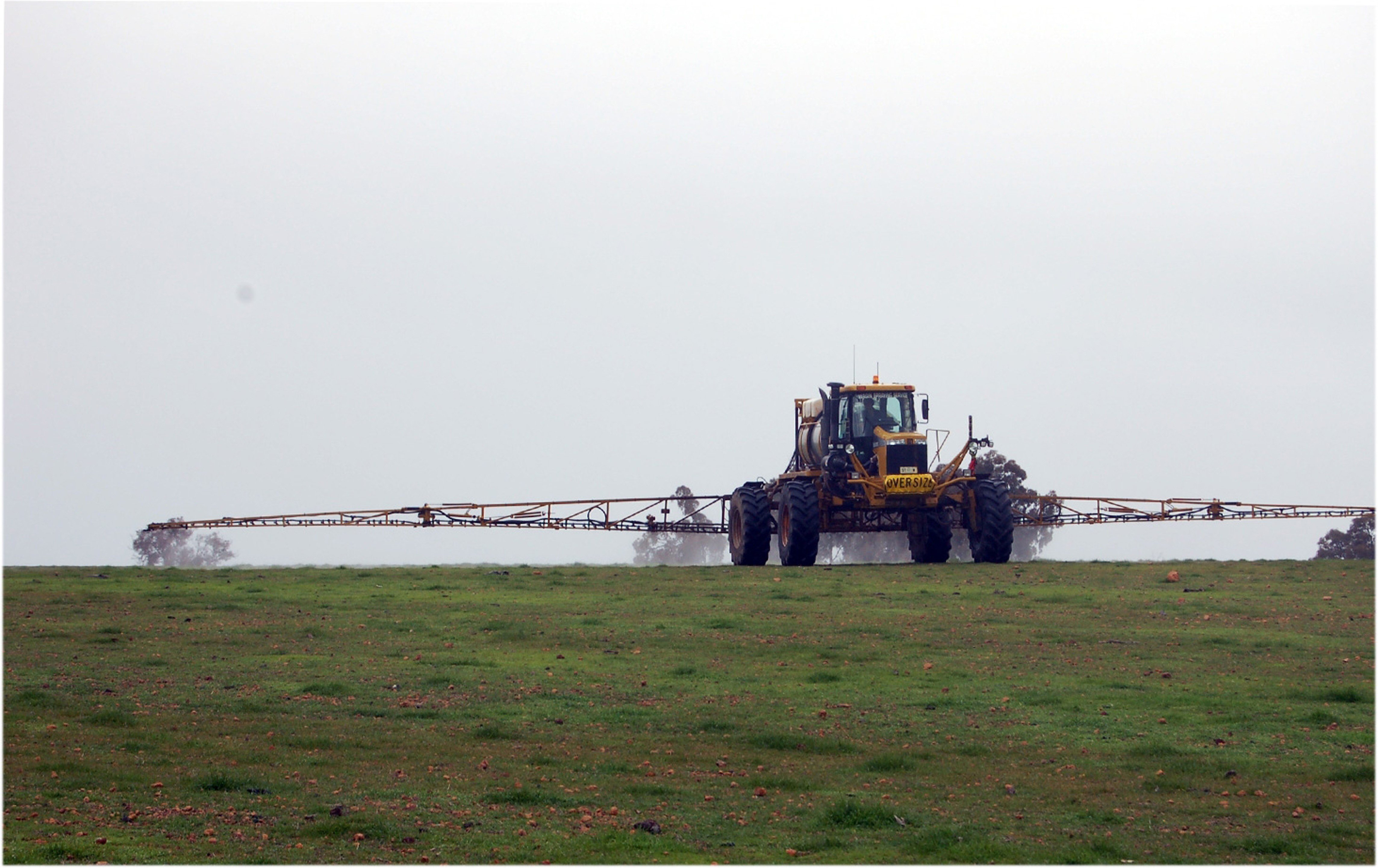 Tractor spraying chemicals on pasture