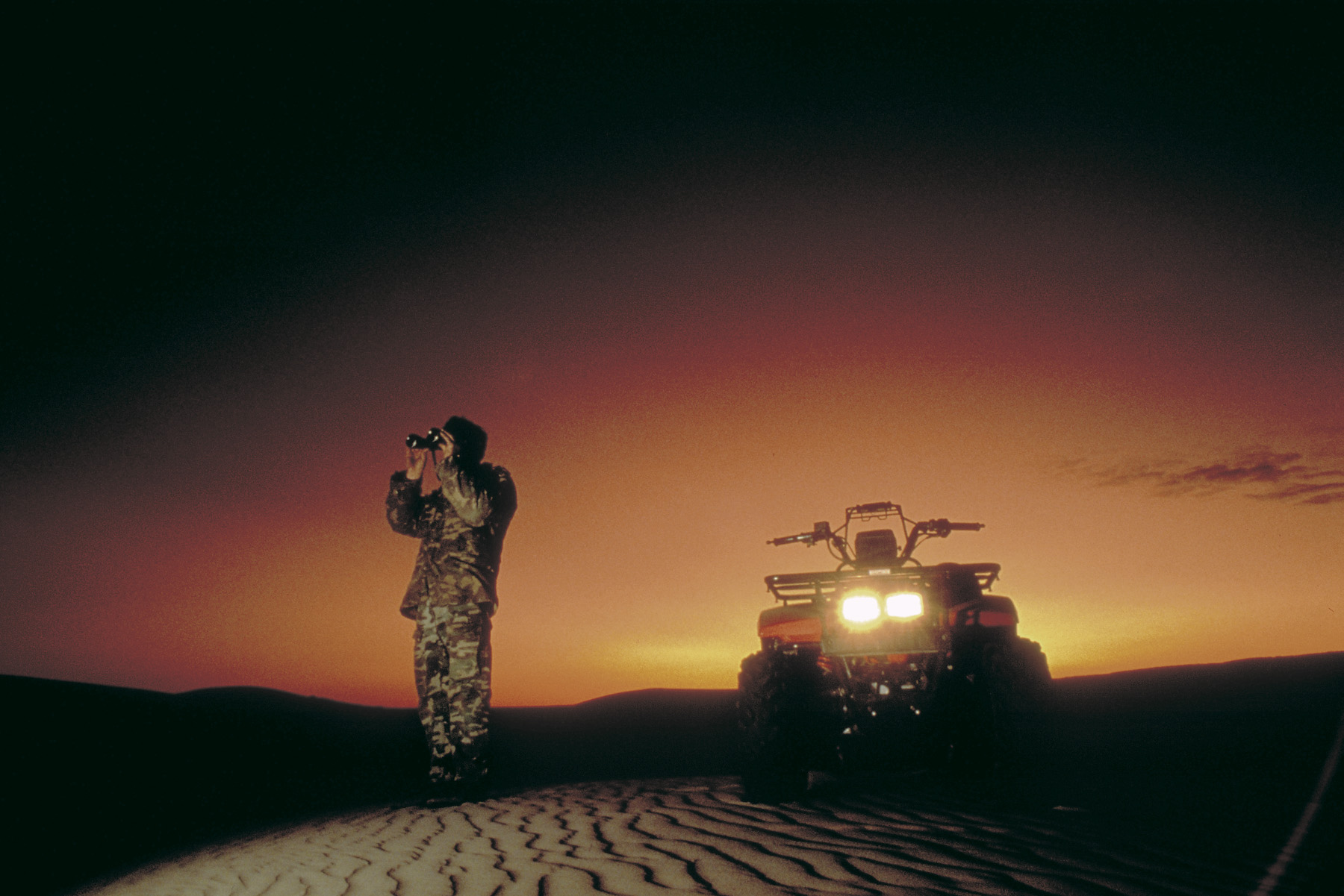 Person at dusk looking through binoculars