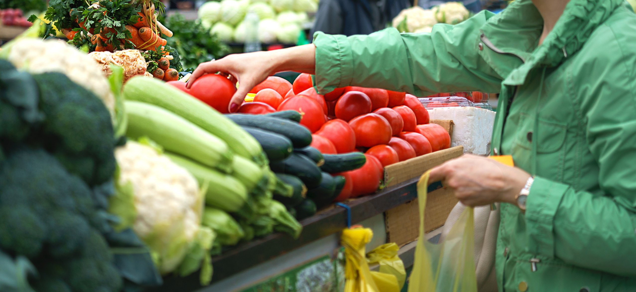 Hands of a female picking fresh vegetables from a cart