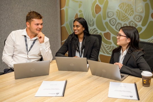 Three graduate employees sitting at desk.