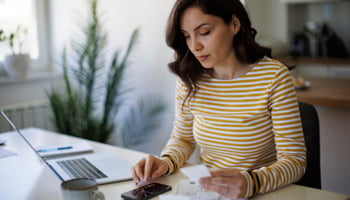 Person at table with laptop and calculator