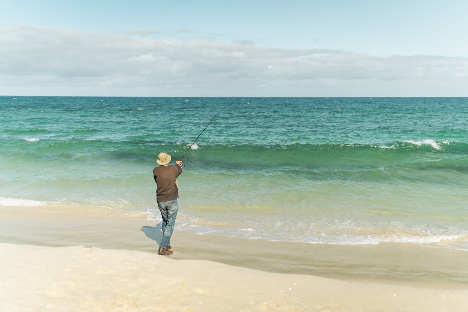 Man casting a rod on a beach