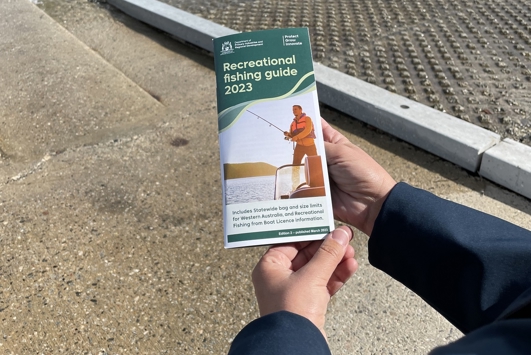 Image of person holding recreational fishing guide brochure