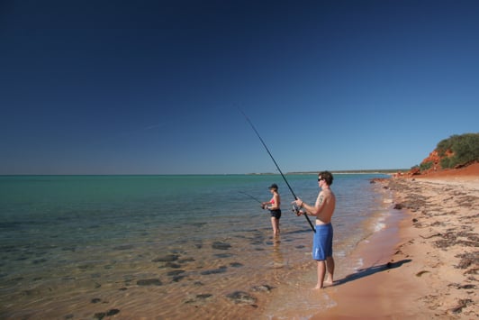 Two people fishing off the beach
